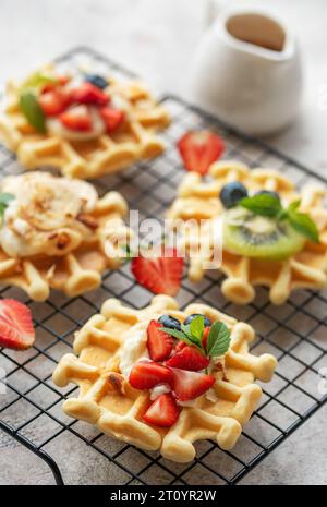 Gaufres fraîchement cuites avec fraises et myrtilles sur un fond gris béton. Cuisson maison. Banque D'Images