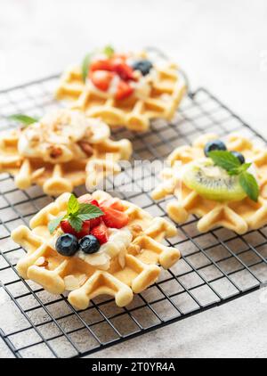 Gaufres fraîchement cuites avec fraises et myrtilles sur un fond gris béton. Cuisson maison. Banque D'Images