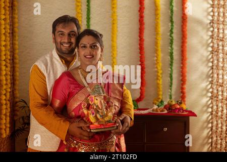 Portrait d'un jeune couple heureux tenant une idole du Seigneur Ganesha Banque D'Images