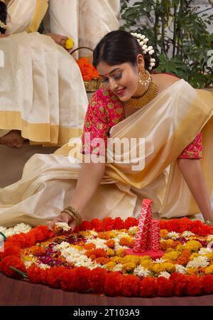 Femme décorant le sol avec des fleurs à l'occasion de Onam Banque D'Images