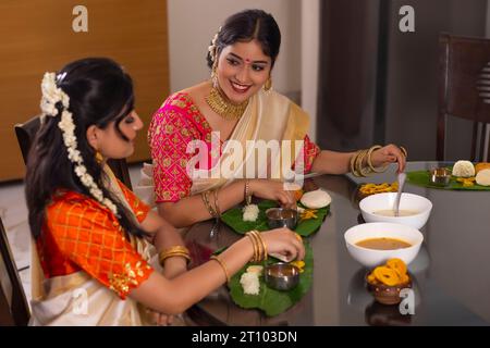 Des femmes heureuses ayant Onam Sadhya ensemble à la maison Banque D'Images