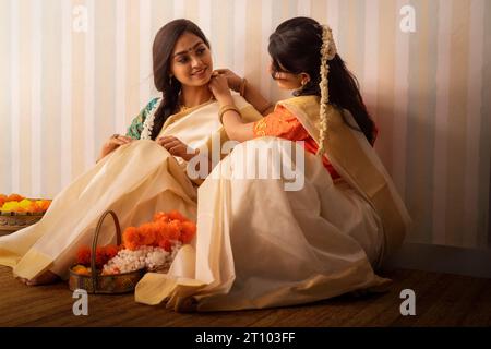 Femmes indiennes du Sud dans des fleurs blanches saree garlanding pour célébrer Onam Banque D'Images