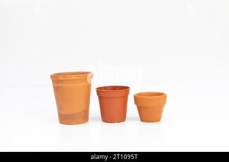 Rangée de pots de plantes en terre cuite vides de différentes tailles et formes isolées sur fond blanc Banque D'Images