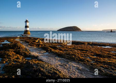 Penmon point sur la côte d'Anglesey, au nord du pays de Galles. Phare de Trwyn du avec Puffin Island derrière. Banque D'Images