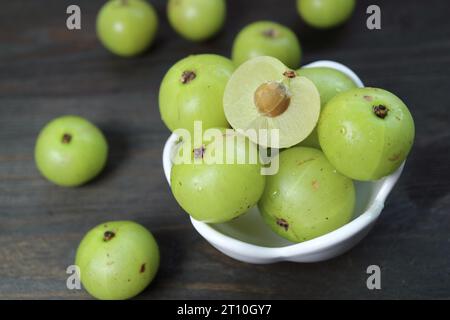 Gros plan de Cut Fresh Amla Berry avec des fruits entiers dispersés autour Banque D'Images