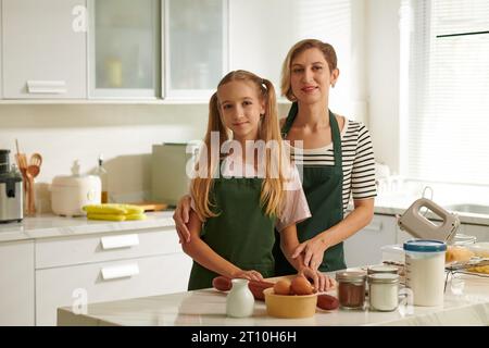 Femme souriante et sa fille adolescente cuisinant le dîner ensemble Banque D'Images