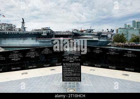 Monument à l'US Navey avec buste de Clifton A. F. Sprague. USS Midway Aircraft Carrier / Museum amarré dans la baie de San Diego en arrière-plan. Banque D'Images