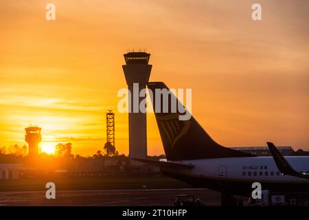 Aéroport de Dublin, Irlande, coucher de soleil et tours de contrôle et avions sur stand. Banque D'Images