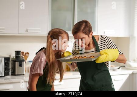 Mère et fille appréciant l'odeur des biscuits au gingembre fraîchement cuits Banque D'Images