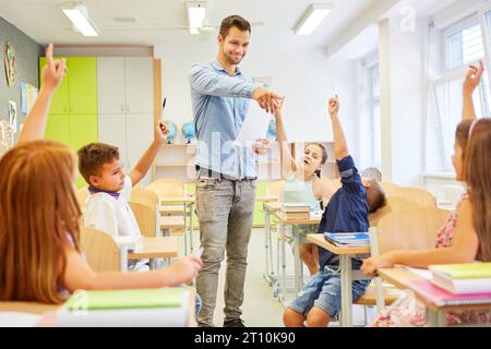 Enseignant souriant pointant du doigt une étudiante assise avec la main levée dans la salle de classe Banque D'Images