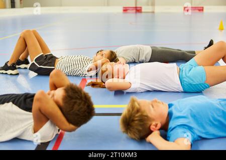 Étudiants masculins et féminins faisant de l'exercice tout en étant couchés sur le sol dans une classe de gym Banque D'Images