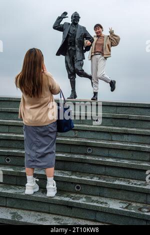 Touristes asiatiques prenant des photos près de la statue d'Eric Morecambe sur le front de mer à Morecambe, Lancashire Banque D'Images