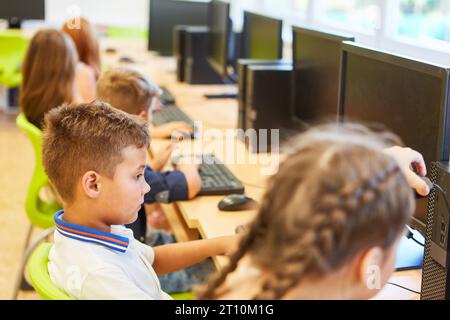 Schoolkid assis avec des amis en classe d'informatique à l'école Banque D'Images