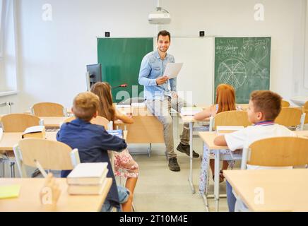 Enseignant masculin enseignant les élèves assis sur un banc dans la salle de classe à l'école Banque D'Images