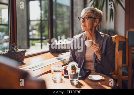 Femme mature est assise dans le café et relaxant. Banque D'Images