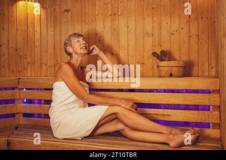Femme mature se détend dans le sauna. Un mode de vie sain pour les personnes âgées. Concept spa. Banque D'Images