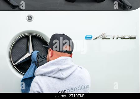 Egestorf, Allemagne. 10 octobre 2023. Un employé nettoie l'étoile Mercedes du nouveau camion long-courrier eActros 600 à l'arrêt camion Hamburg-Nordheide avant la présentation. Le constructeur de véhicules utilitaires Daimler Truck a présenté la version série de son camion long-courrier électrique à batterie, le Mercedes-Benz eActros 600. Crédit : Jonas Walzberg/dpa/Alamy Live News Banque D'Images