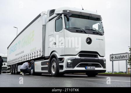 Egestorf, Allemagne. 10 octobre 2023. Un employé nettoie le nouveau camion long-courrier eActros 600 à l'arrêt « Hamburg-Nordheide » avant la présentation. Le constructeur de véhicules utilitaires Daimler Truck a présenté la version série de son camion long-courrier électrique à batterie, le Mercedes-Benz eActros 600. Crédit : Jonas Walzberg/dpa/Alamy Live News Banque D'Images