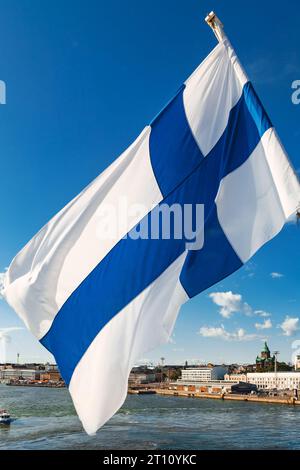 Agitant le drapeau finlandais sur un ferry de croisière avec le paysage urbain d'Helsinki en arrière-plan, la Finlande, la Scandinavie Banque D'Images