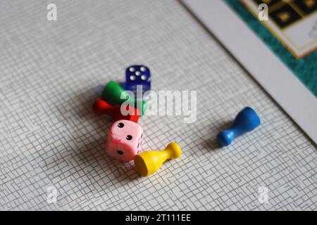 Prêt pour un jeu de plateau. Jetons colorés et dés de jeu disposés sur une table de cuisine. Jeu de table pour toute une famille. Mise au point sélective. Flou Banque D'Images