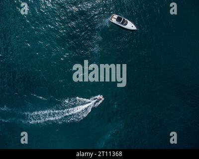 Vue aérienne de dessus vers le bas du bateau à moteur de vitesse et scooter flottant sur la mer bleue ouverte Banque D'Images