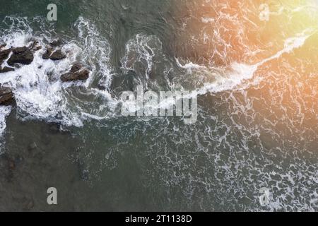 Côte peu profonde avec de l'eau verte de mer rocheuse avec des vagues de mousse aérienne au-dessus de la vue du drone en journée ensoleillée Banque D'Images