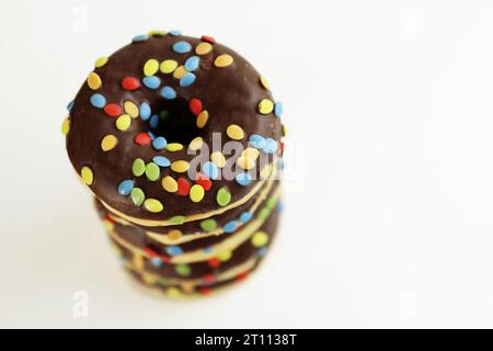 Une pile de beignets glacés au chocolat et aux smarties colorées. Pile de 5 beignets isolés sur fond blanc. Vue de dessus. Espace de copie Banque D'Images