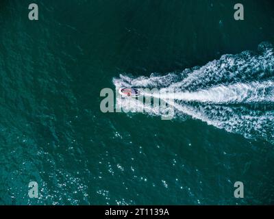 Vue aérienne de haut en bas du scooter flottant sur la mer bleue à la journée ensoleillée. Banque D'Images