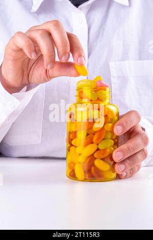 Vitamines Gummy et supplément pour adultes. La femme mange des micro-éléments de bonbons multivitaminés de gelée sucrée à partir de bouteilles de pilules transparentes, de médicaments modernes et Banque D'Images