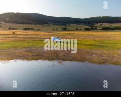 Vue aérienne de dessus d'un camping-car garé sur une plage, paysage de chaîne de montagnes Banque D'Images