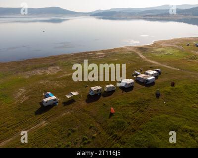 Vue aérienne de dessus d'une fourgonnette de camping garée sur une plage, paysage de chaîne de montagnes Banque D'Images