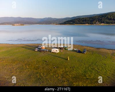 Vue aérienne de dessus d'une fourgonnette de camping garée sur une plage, paysage de chaîne de montagnes Banque D'Images