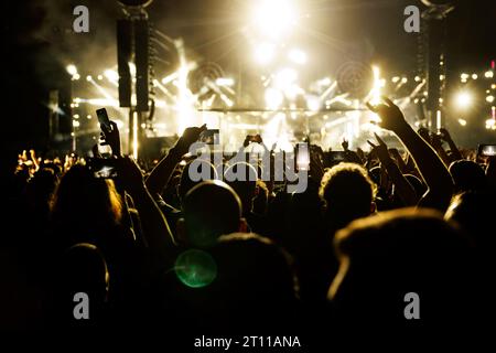 Des gens heureux se pressent les mains levées sur une piste de danse pendant un concert Banque D'Images