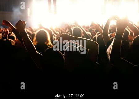 Des gens heureux se pressent les mains levées sur une piste de danse pendant un concert Banque D'Images