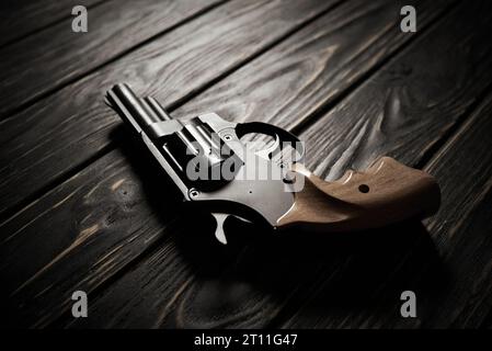 Pistolet revolver noir sur fond en bois foncé Banque D'Images