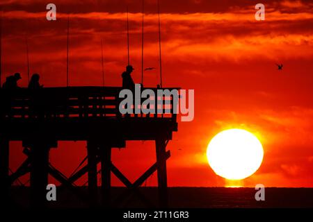 Île de Palms, États-Unis. 10 octobre 2023. Les pêcheurs silhouettes par le lever du soleil alors qu'ils jettent pour le matin à prendre au large de Sea Cabins Pier par un matin froid dans le bas pays, le 10 octobre 2023 à Isle of Palms, Caroline du Sud. Crédit : Richard Ellis/Richard Ellis/Alamy Live News Banque D'Images