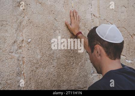 Main de l'homme priant sur le mur Occidental à Jérusalem. Touriste dans un tas sur sa tête tenant le mur en pleurant. Banque D'Images