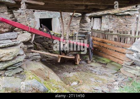 Chariot de bœuf en bois rouge niché dans un bâtiment rural en pierre, Asturies, Espagne Banque D'Images