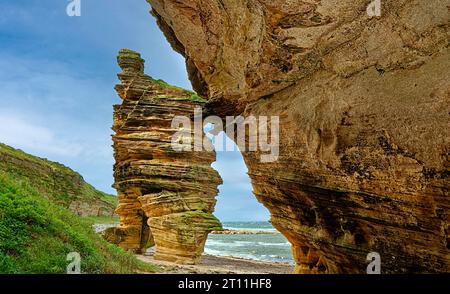 Hopeman Moray Coast Scotland regardant d'une grotte de grès sculpté coloré en grès patiné vers un empilement marin géant Banque D'Images