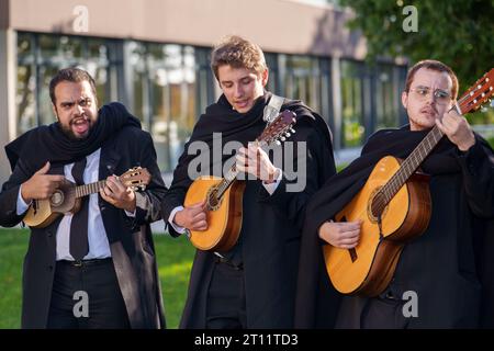 Les étudiants en tenue académique traditionnelle et cape noire chantent et jouent des instruments de musique en tant que membres de l'Estudantina Universitária de Coimbra Banque D'Images