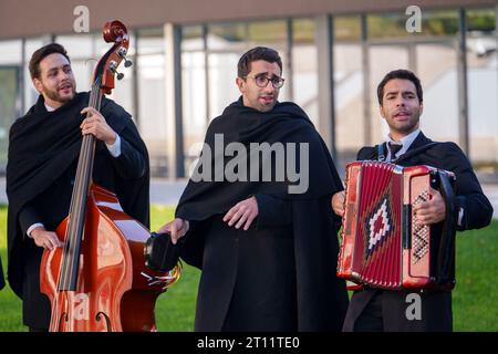 Les étudiants en tenue académique traditionnelle et cape noire chantent et jouent des instruments de musique en tant que membres de l'Estudantina Universitária de Coimbra Banque D'Images