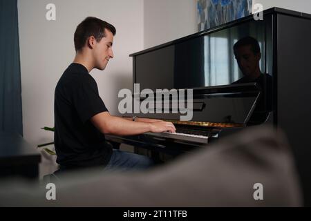 Jeune homme pratiquant le piano à la maison Banque D'Images