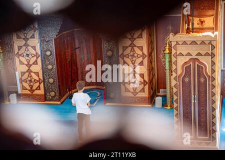 L'enfant prie à l'intérieur de la mosquée derrière Imam place Banque D'Images