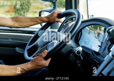 Gros plan du conducteur du camion derrière le volant dans une cabine. Banque D'Images