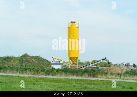 Un conteneur jaune pour bétonnières et un ascenseur pour charger des camions à benne basculante. Banque D'Images