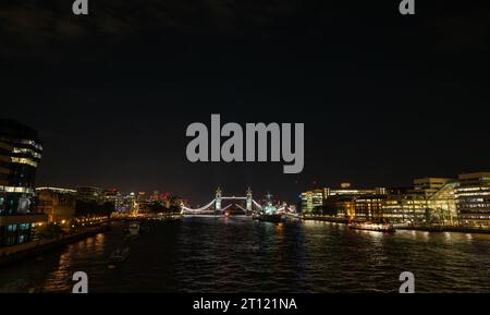 Londres, Royaume-Uni : vue de nuit sur la Tamise depuis le London Bridge en regardant vers un Tower Bridge ouvert. HMS Belfast devant. Banque D'Images