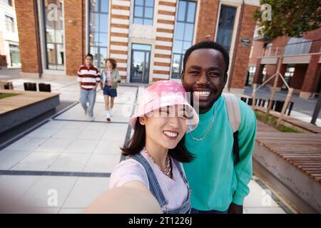 POV de deux jeunes étudiants ethniques prenant la photo selfie ensemble sur le campus de l'université et souriant à la caméra joyeusement Banque D'Images