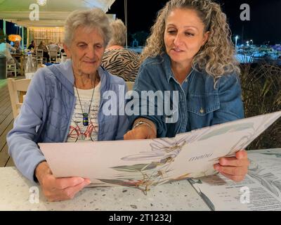 Malia, Crète, Grèce, Europe, 01 OCT 2023. Femmes lisant un menu dans un restaurant grec, Malia, Crète. Banque D'Images