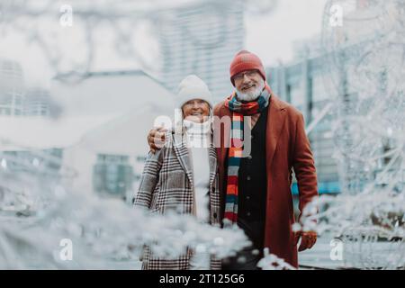 Élégant couple senior marchant près de la rivière, pendant la journée froide d'hiver. Banque D'Images