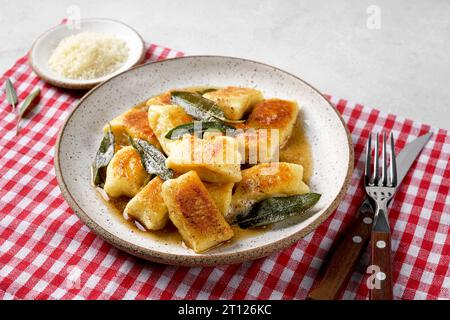 Gnocchi maison italien avec pommes de terre, fromage et beurre de sauge, servi dans une assiette sur une serviette rouge Banque D'Images